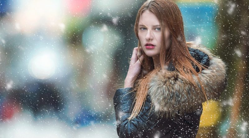 woman standing in falling snow looking at camera