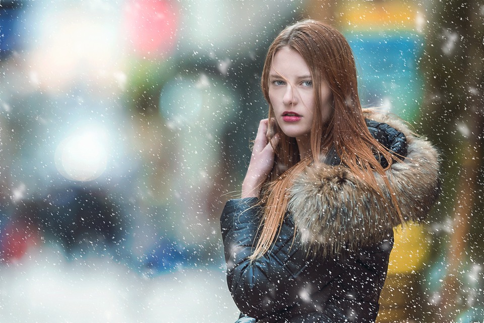 woman standing in falling snow looking at camera