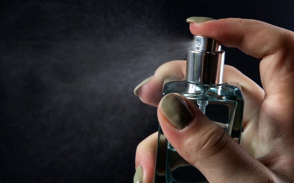 woman's finger misting perfume bottle that may be a dupe