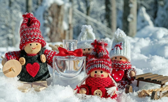 two elves by in the snow with a bottle of perfume between them 